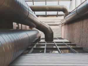 Industrial HVAC ductwork system mounted on a modern building exterior, viewed from below.